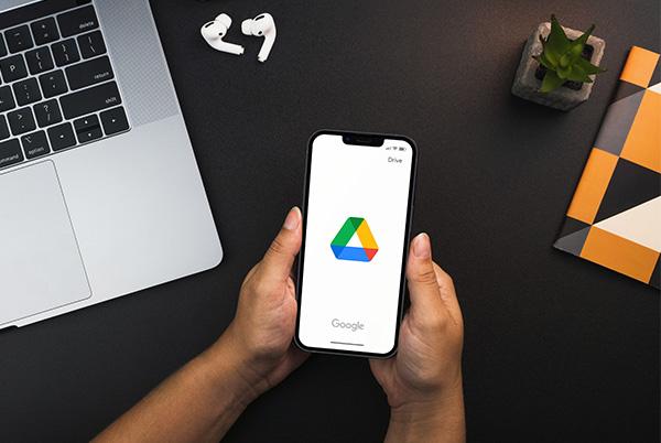 google drive app phone screen hands desk laptop
